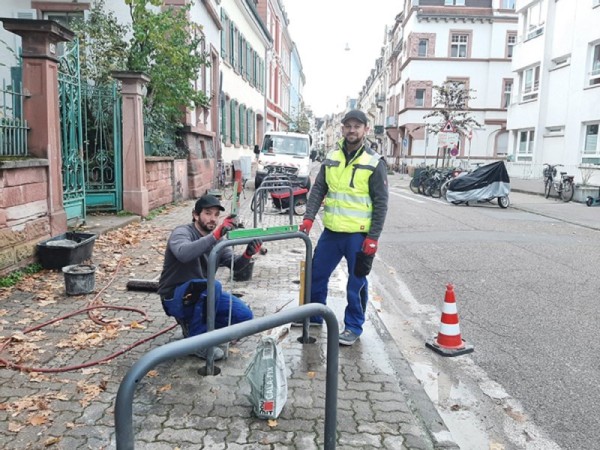 Mehr Abstellmöglichkeiten für Fahrräder, weniger Platz für illegales Gehwegparken: zwei Mitarbeiter der städtischen Schlosserei bei der Installation von Fahrradabstellanlagen in der Gaisbergstraße. (Foto: Stadt Heidelberg) Zwei Arbeiter beim Montieren