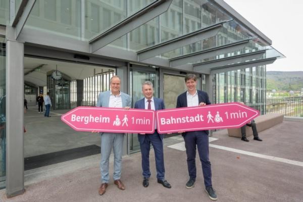 Oberbürgermeister Eckart Würzner (l.), Erster Bürgermeister Jürgen Odszuck (r.) und Kai M. Dreesbeimdiek, Geschäftsführer der Gustav Zech Stiftung Management GmbH, eröffnen die neue Fußgängerbrücke zwischen Hauptbahnhof und Europaplatz und halten dabei Pfeile mit der Aufschrift Bergheim und Bahnstadt